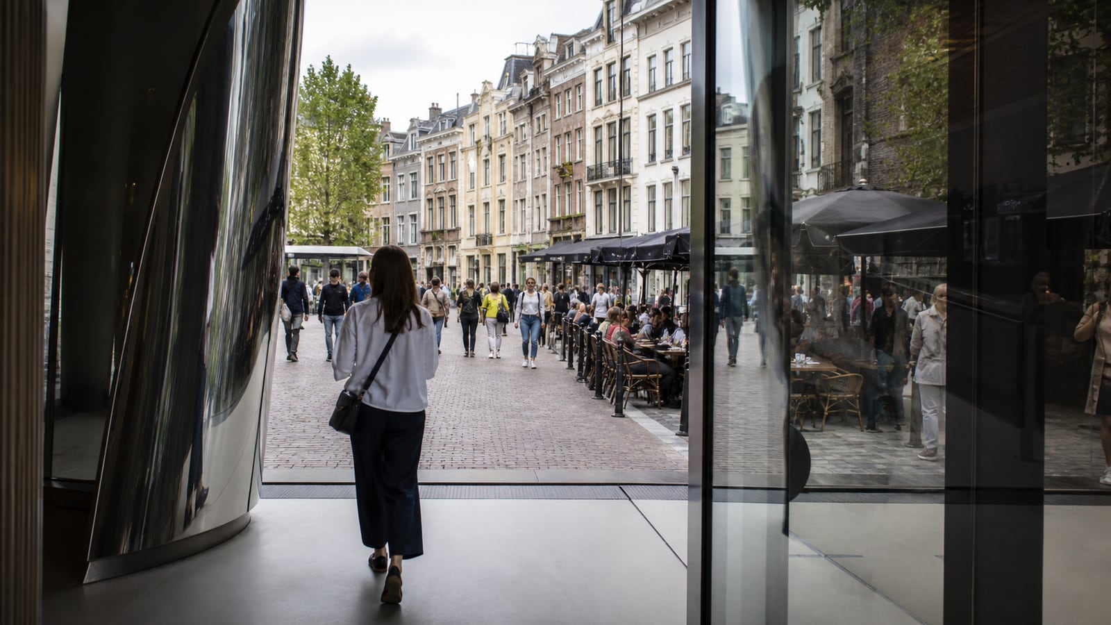 Bezoeker verlaat een museum aan een levendige Europese stadsstraat