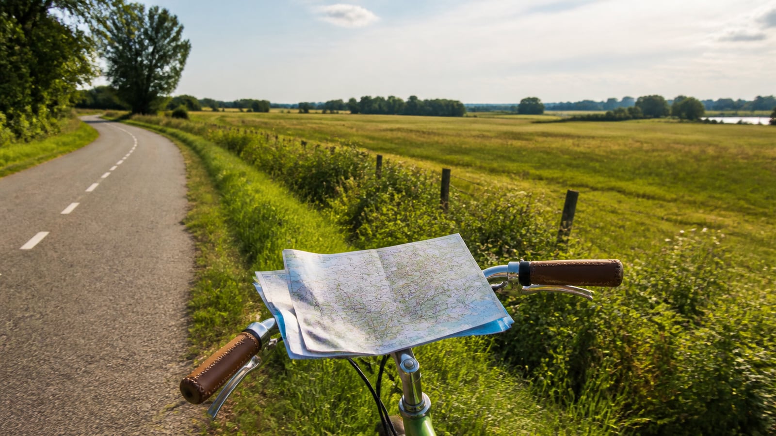 Fiets met een kaart op het stuur langs een landelijke bochtige weg